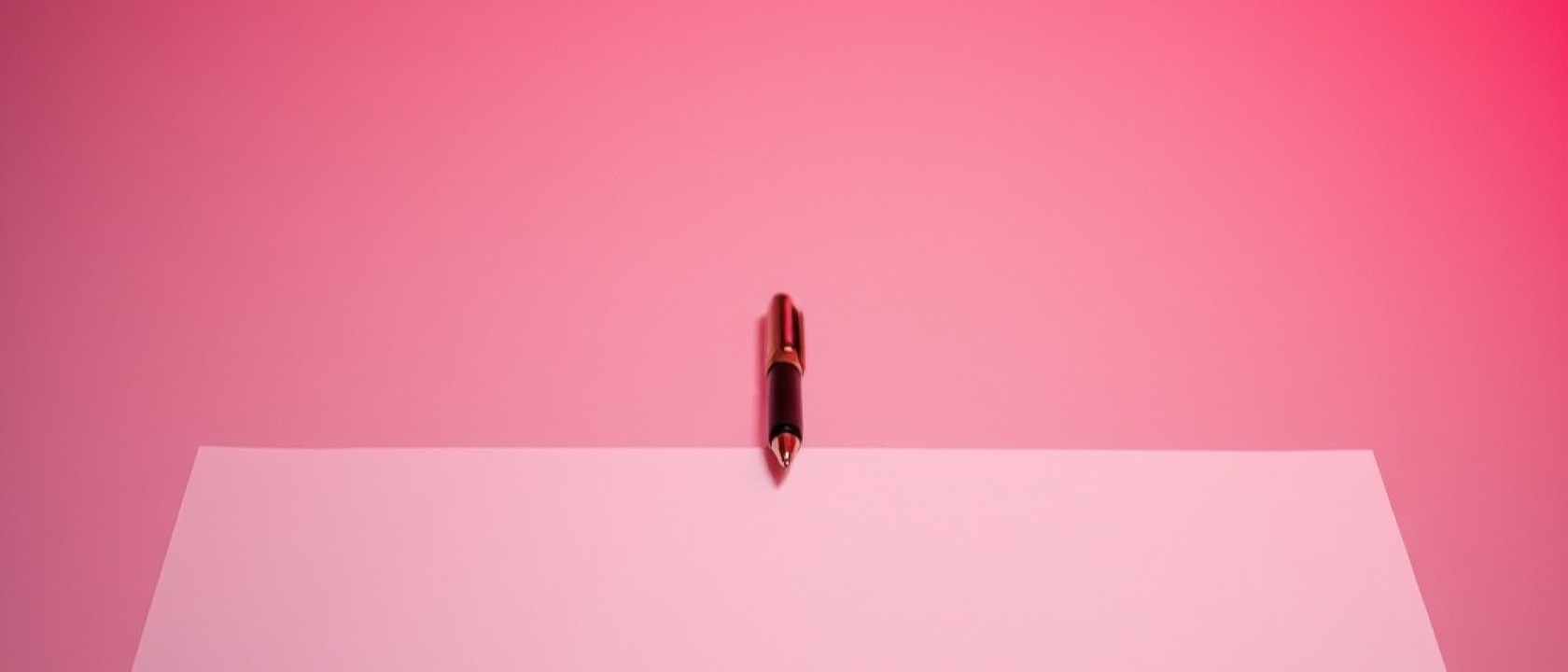 A hand holding a pen above a blank sheet of paper